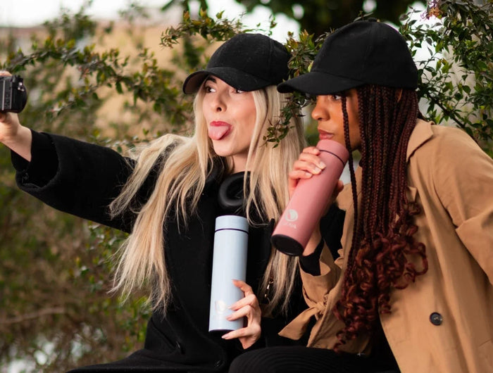 Deux femmes profitant d’une pause en plein air avec la bouteille LED et le mug isotherme Obéna. Hydratation optimisée au quotidien.