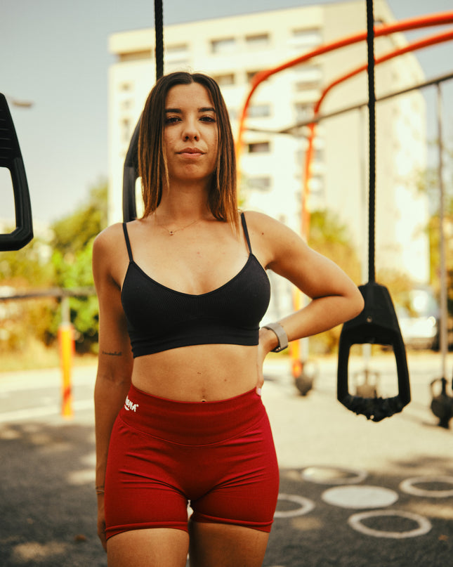 Femme debout en extérieur portant le short de sport Obéna Féline bordeaux, pose confiante dans un cadre fitness urbain.